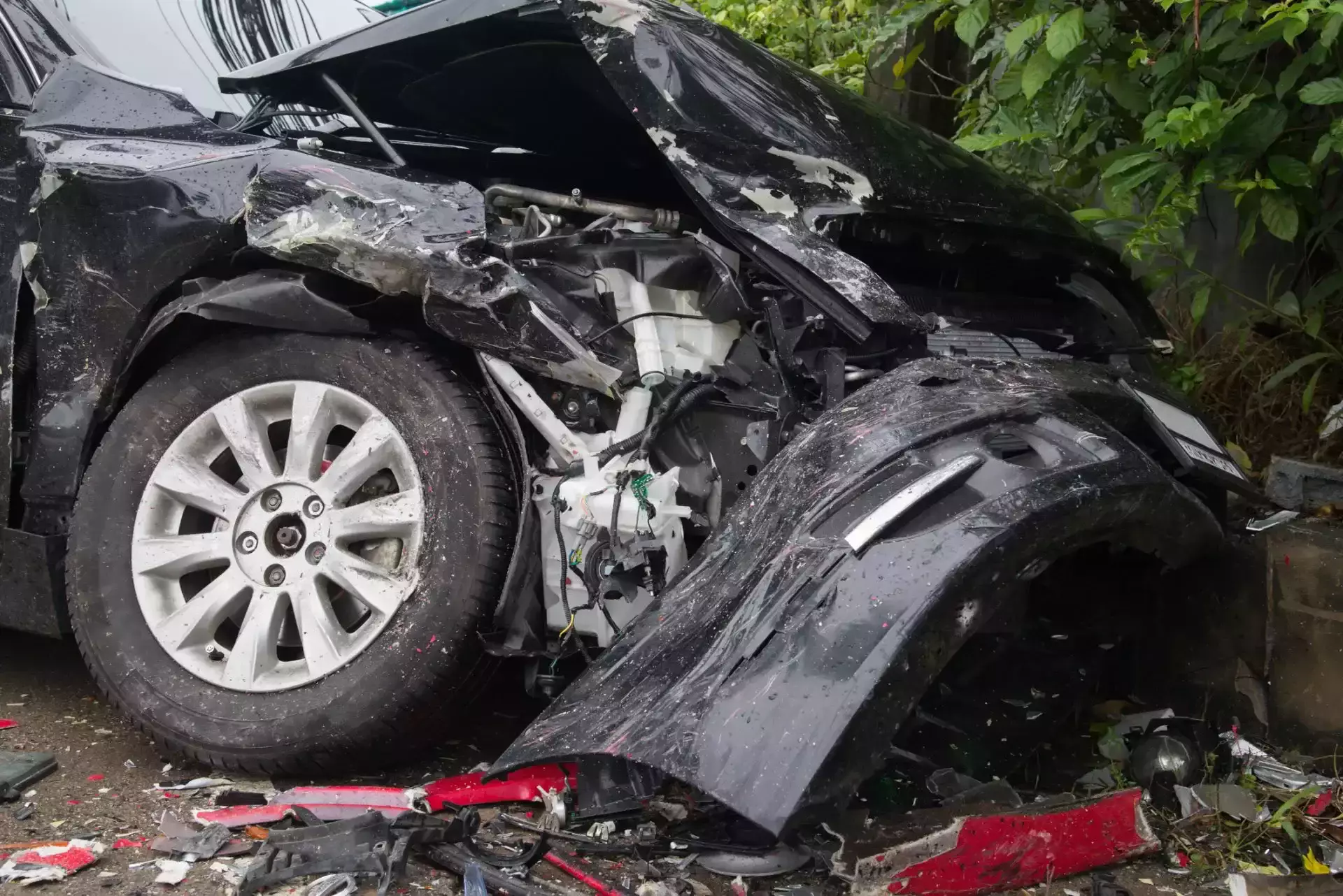 Severely damaged black car with extensive front-end damage following a collision.